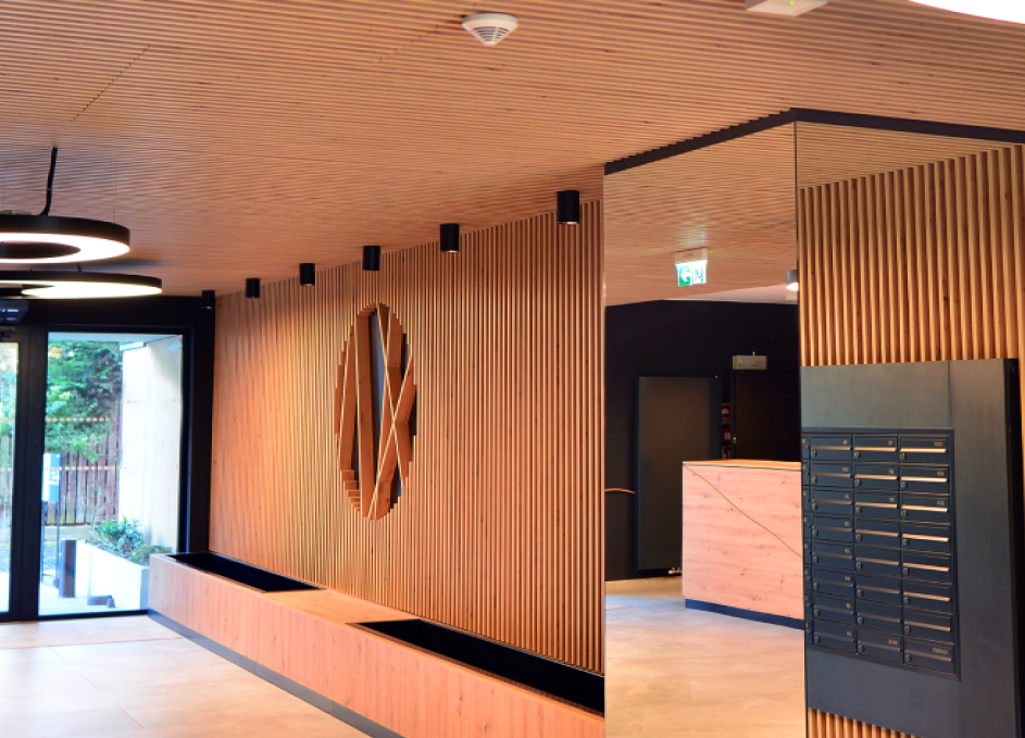 Moderner Eingangsbereich mit vertikaler Holz-Lamellenverkleidung an Wand und Decke. Die Akustikpaneele in warmem Holzton sorgen für eine elegante und strukturierte Optik.