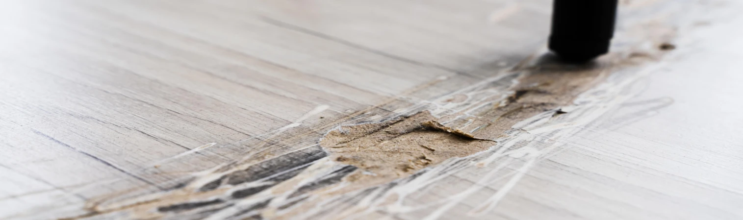 Coverbild für Ratgeber über Vinylboden reparieren. Nahaufnahme einer beschädigten Vinylbodenfläche mit tiefem Kratzer und aufgetragener Reparaturmasse, vorbereitet zur Ausbesserung mit einem Reparaturwerkzeug.