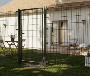 Doppelstabmattenzaun mit passendem Tor vor einem Haus mit Garten.