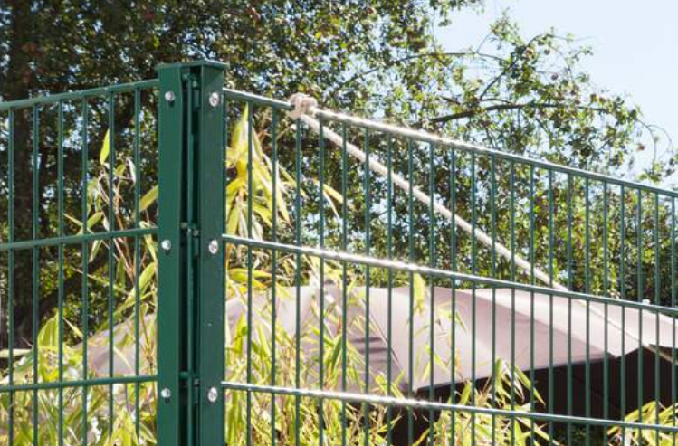 Ein grüner Doppelstabmattenzaun mit Eckpfosten als Grundstücksbegrenzung.