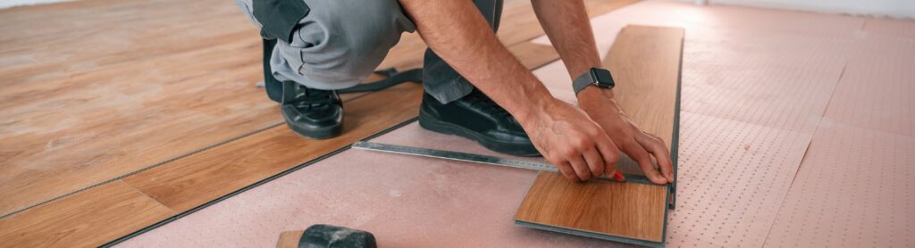 Mann verlegt Vinylboden mit Werkzeug