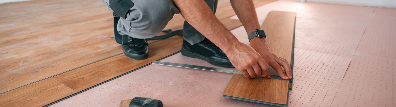 Mann verlegt Vinylboden mit Werkzeug