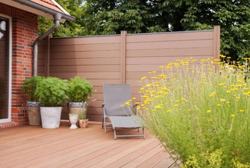 Brauner WPC-Sichtschutzzaun mit horizontalen Elementen, der deiner Terrasse eine gemütliche Atmosphäre verleiht.