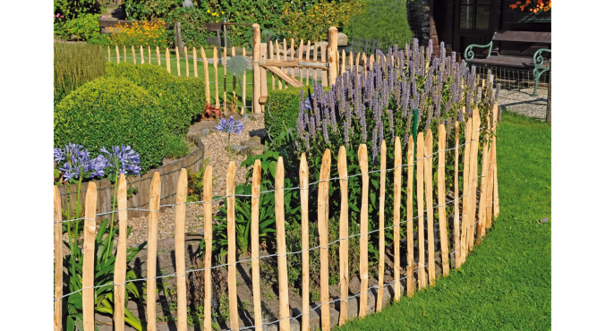 Staketenzaun aus naturbelassenem Holz mit Drahtverbindung um ein Gartenbeet mit Blumen und Sträuchern.