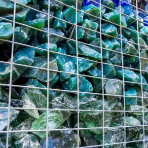 Gabionenzaun mit blaugrünen Glassteinen als dekorative Füllung.